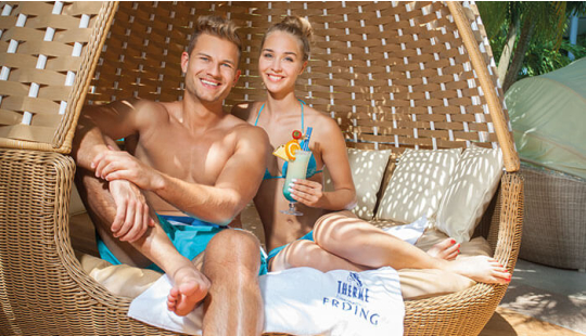 Ein Paar sitzt gemeinsam in einem Family Relax Egg aus Rattan.